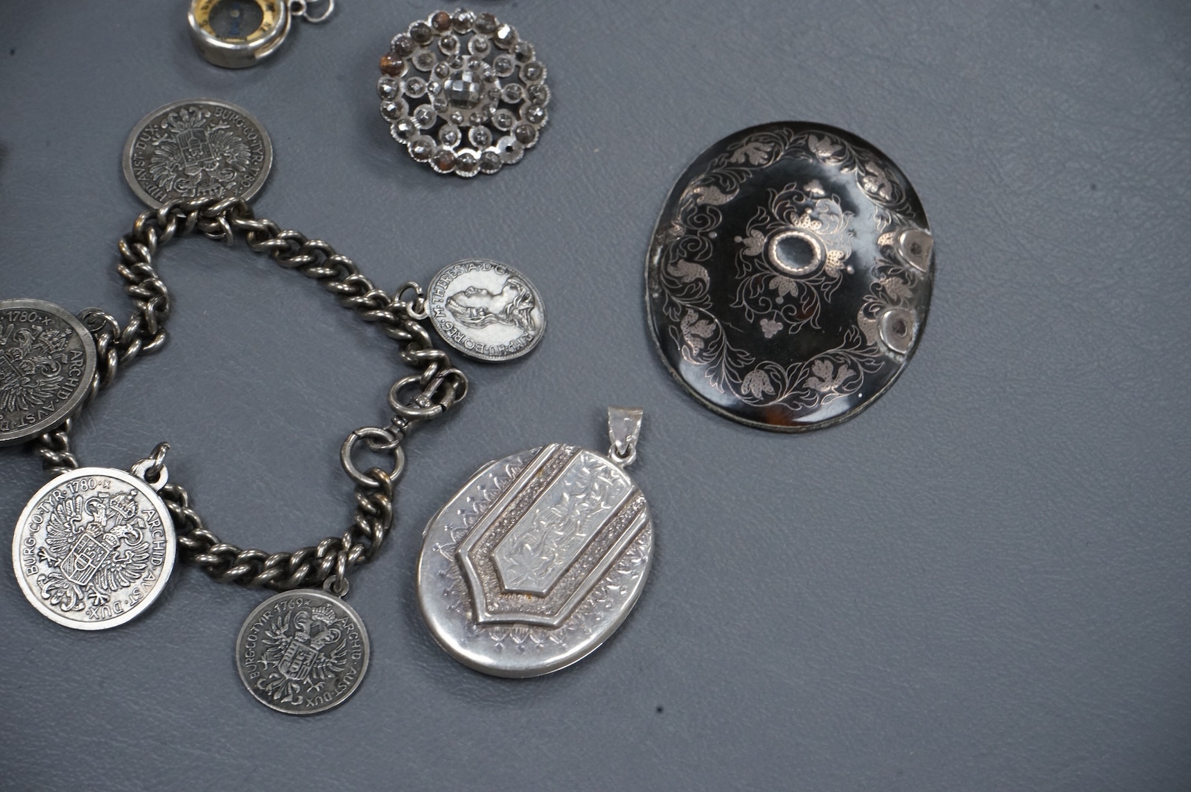 A mixed group of assorted collectables including a silver vesta case, two Victorian white metal lockets, two cut steel buttons, a coin bracelet and three other items.